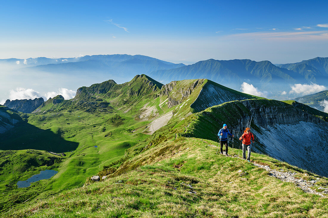 Mann und Frau beim Wandern steigen über Wiesenrücken zum Monte Pavione auf, Monte Pavione, Belluneser Dolomiten, Venezien, Venetien, Italien