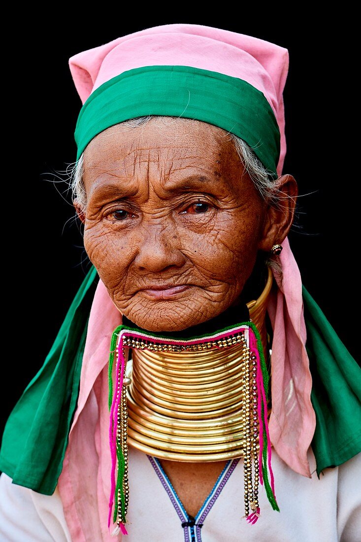 Head portrait of a Kayan Lahwi woman with brass neck coils and traditional clothing. The Long Neck Kayan (also called Padaung in Burmese) are a sub-group of the Karen ethnic from Burma. They wear spiral coils around their neck and lower legs.They are also nicknamed "giraffe women“.The neck itself is not lengthened; the appearance of a stretched neck is created under the pressure of the collar, the ribs lower and the shoulders and clavicles collapse. Pan Pet Region, Kayah State, Myanmar