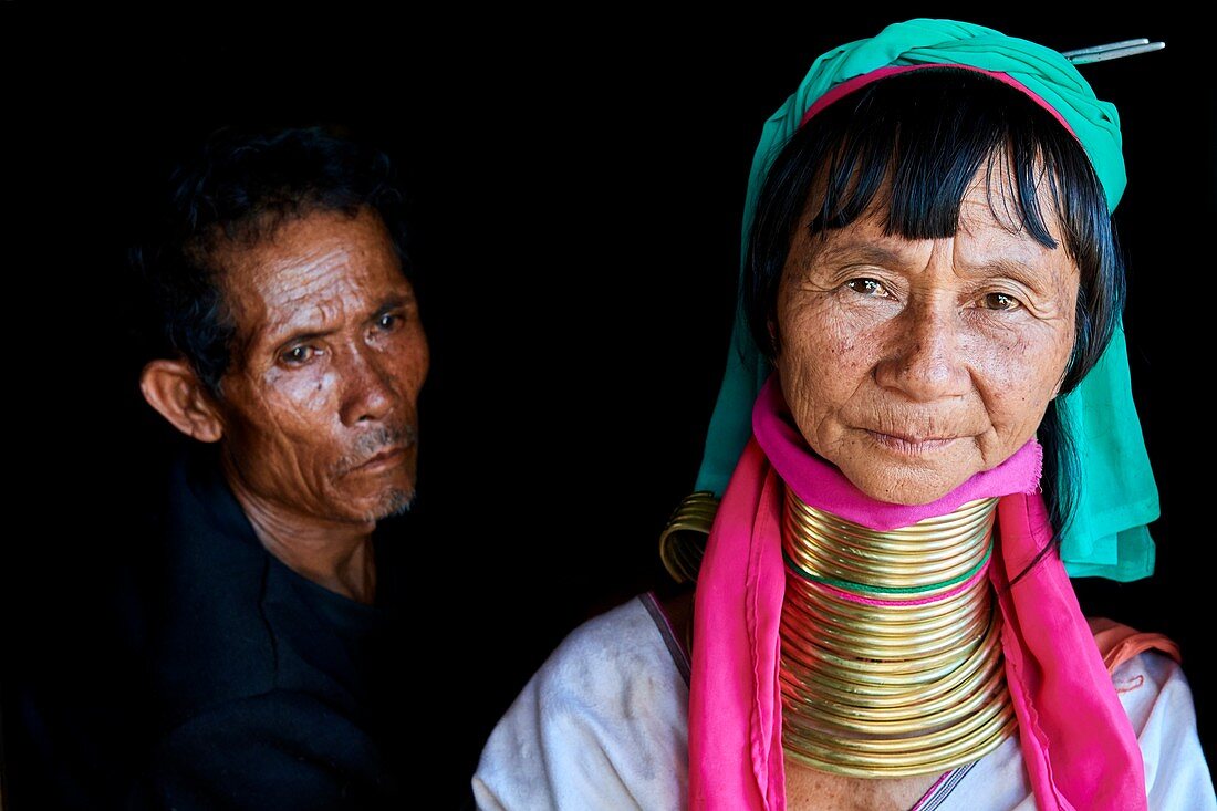 Portrait of a Kayan Lahwi woman with her husband. The Long Neck Kayan (also called Padaung in Burmese) are a sub-group of the Karen ethnic from Burma. They wear spiral coils around their neck and lower legs.They are also nicknamed "giraffe women“. The neck itself is not lengthened; the appearance of a stretched neck is created under the pressure of the collar, the ribs lower and the shoulders and clavicles collapse. Pan Pet Region, Kayah State, Myanmar