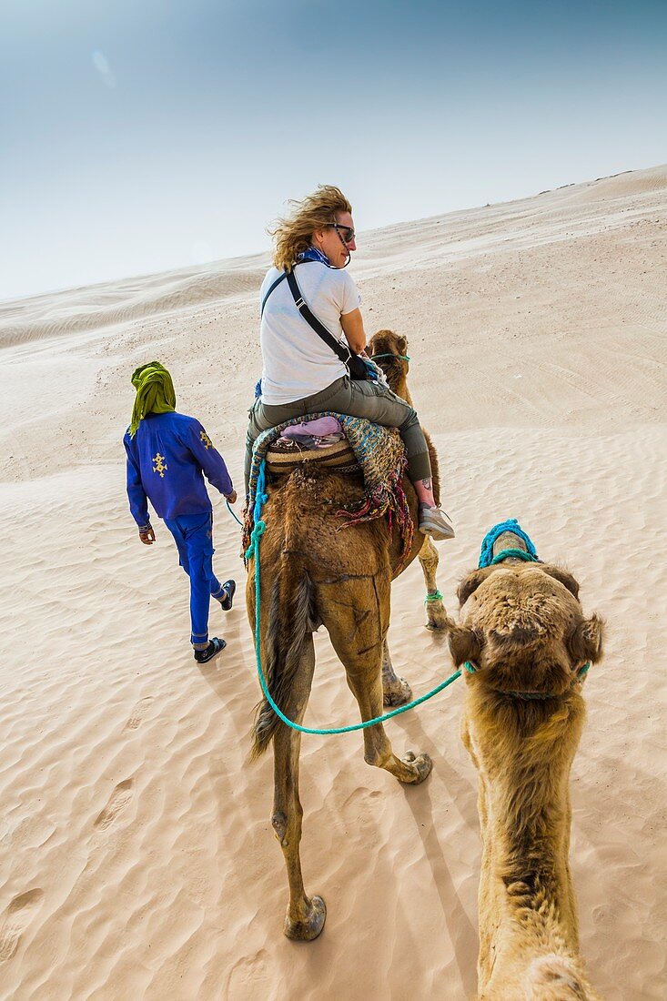 Frau und Führer bei einer Dromedarfahrt in der Wüste, Douz, Tunesien, Afrika