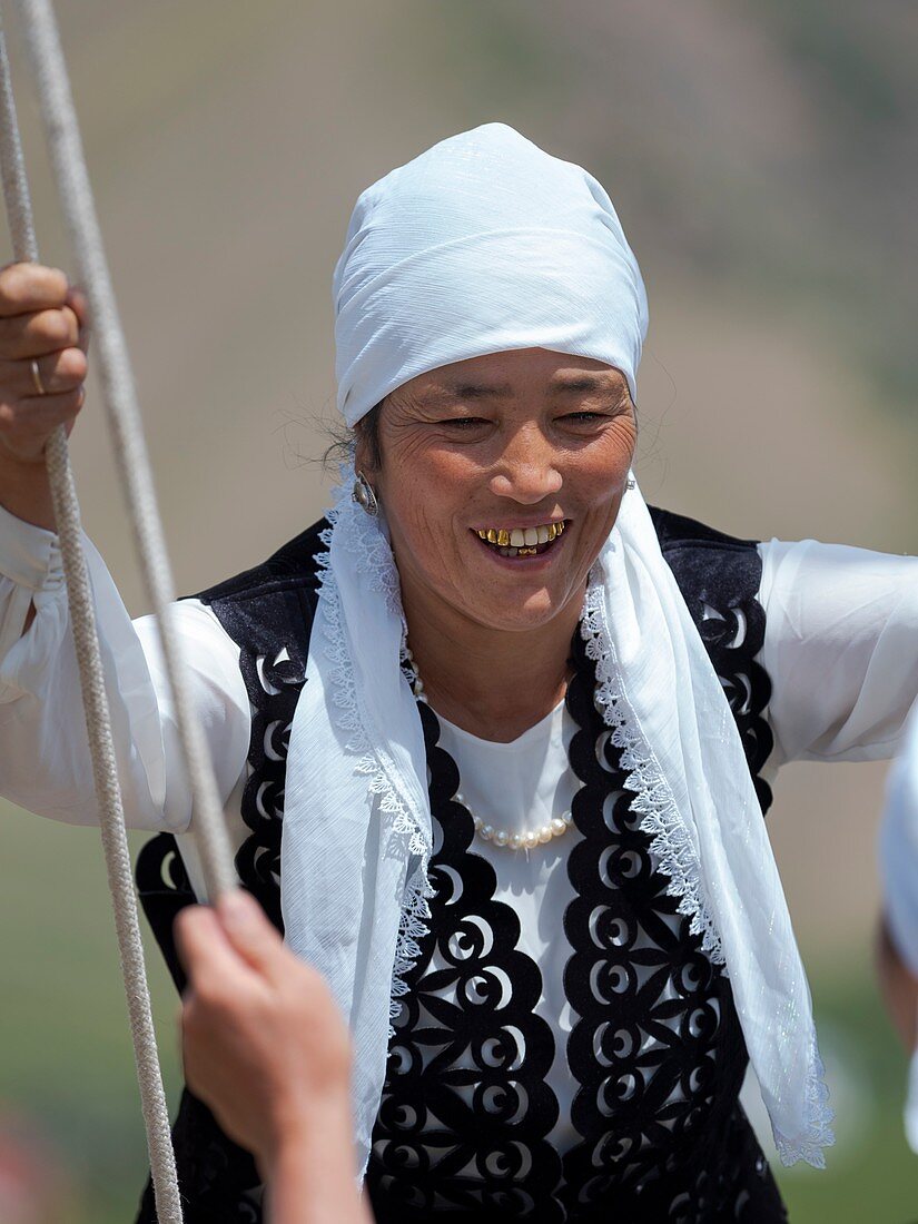 Frau in traditioneller Tracht amüsiert sich auf einer Schauke, Volksfest zum Gedenken an den Ursprungsmythos des Tien Shan Maral (Tian Shan wapiti), einem Ursprungsmythos der kirgisischen Stämme, in der Nähe von Tasch Baschat, Region Naryn, Asien, Zentral-Asien, Kirgisistan
