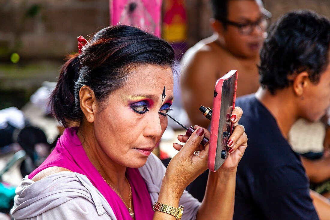 Eine Frau trägt Make-up auf, bevor sie in einer traditionellen balinesischen Barong- und Kris-Tanzshow auftritt, Batabulan, Bali, Indonesien
