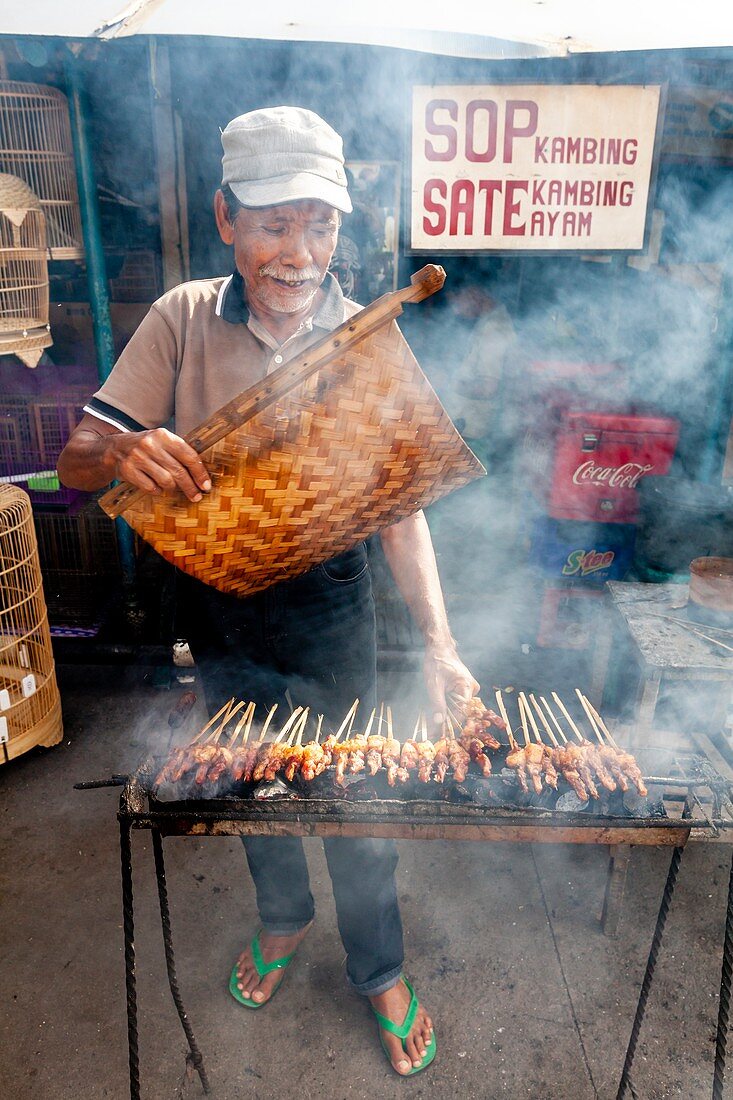 An Indonesian Man Cooking/Grilling Meat In The Street, Jakarta, Indonesia.