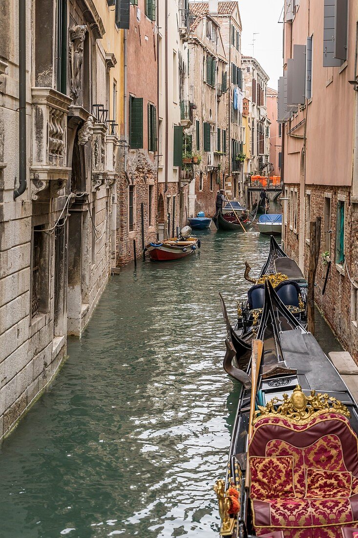 Venedig, Italien - 30. Oktober 2019: Stadtbild mit Booten und Gondeln im engen Kanal, aufgenommen am 30. Oktober 2019 im hellen wolkigen Herbstlicht in Venedig, Venetien, Italien