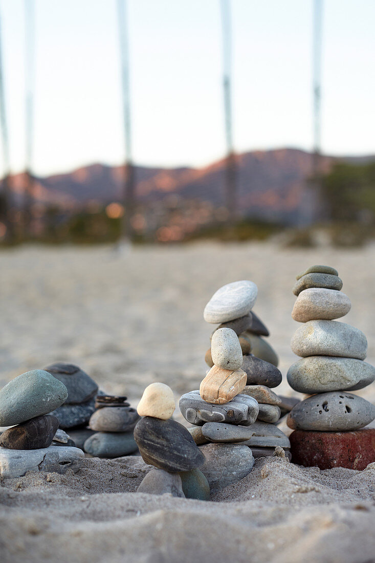 Piled stones on the beach in the evening light with a view of the Santa Ynez Mountains in Santa Barbara, California, USA.