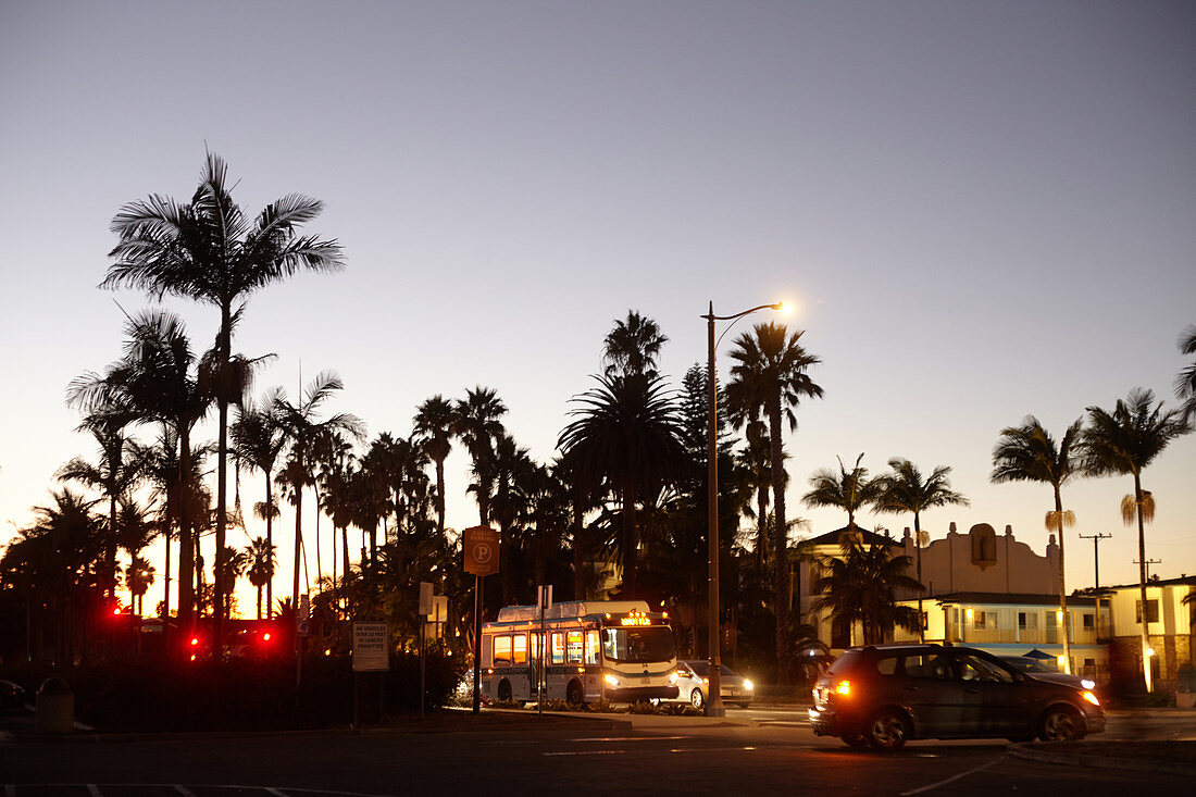 Palm trees and traffic at night on East Cabrillo Boulevard in Santa Barbara, California, USA.