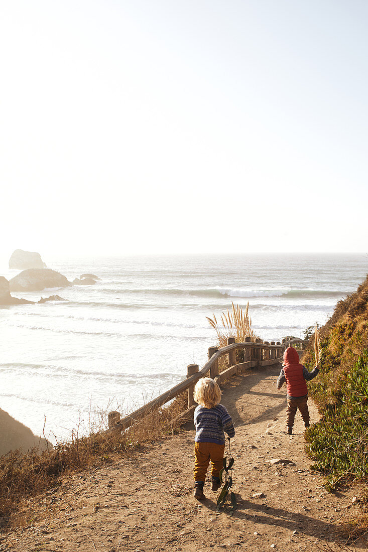 Kinder laufen einen Spazierpfad entlang bei Big Sur, Kalifornien, USA.