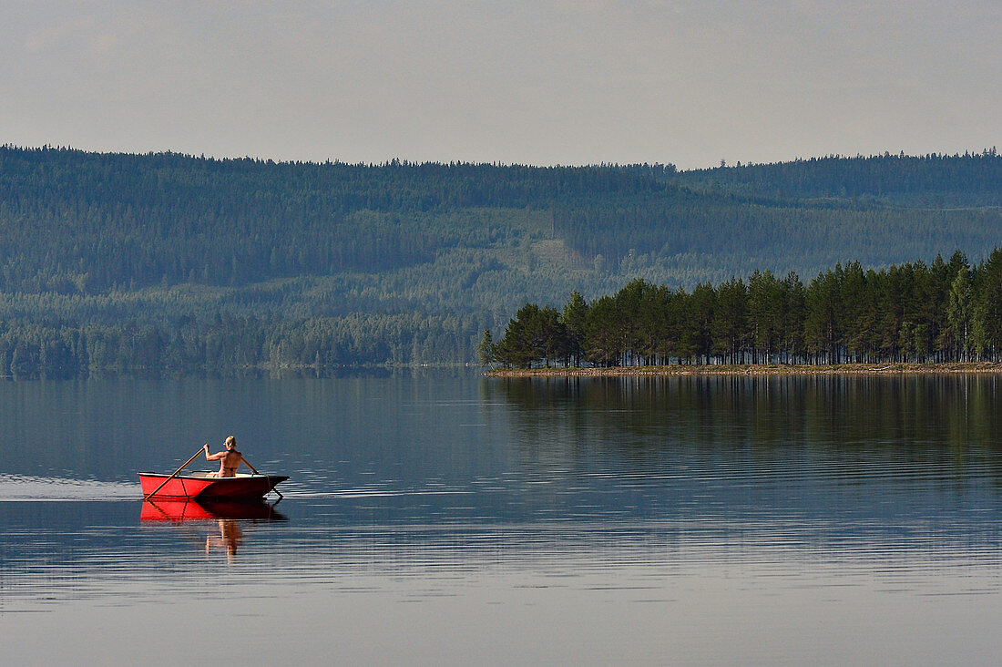 Young woman in a row boat, Orsjön, Tomterna, Västernorrbotten, Sweden