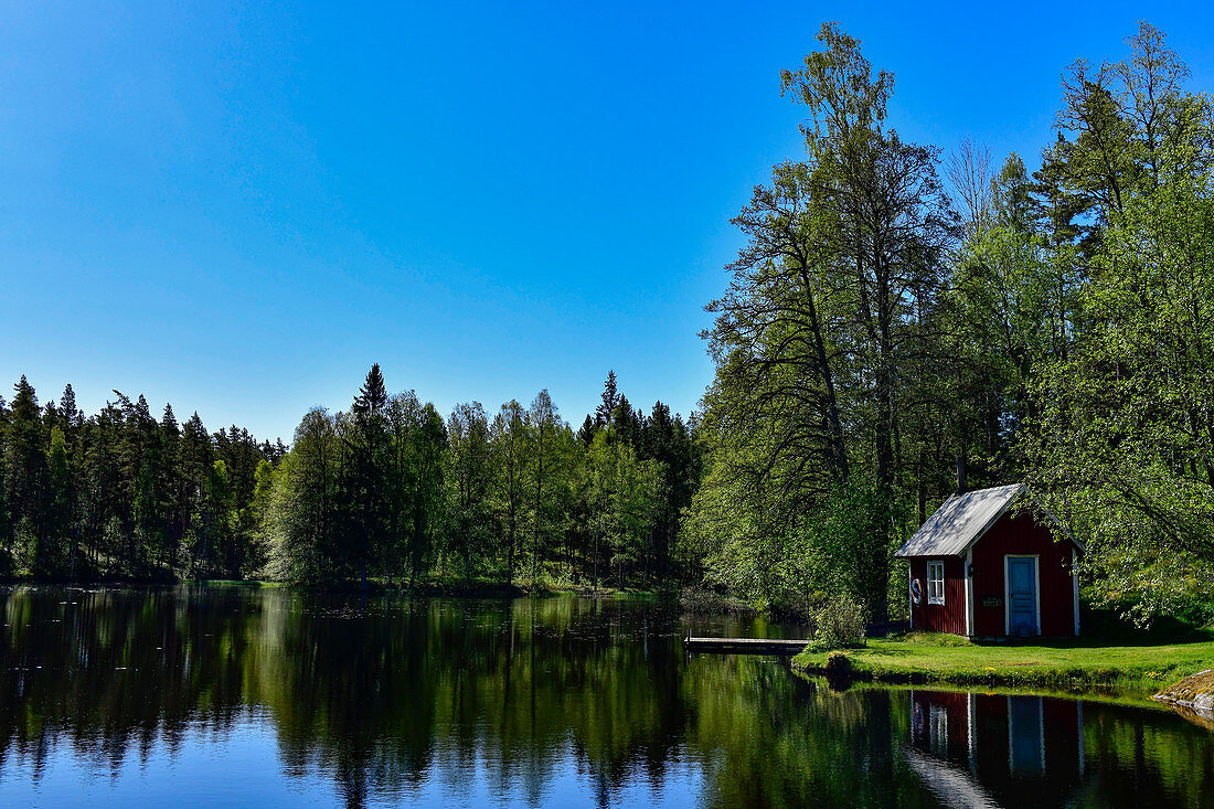 Eine kleine Hütte mit Steg am See mitten im Wald bei Stengårdshult, Schweden