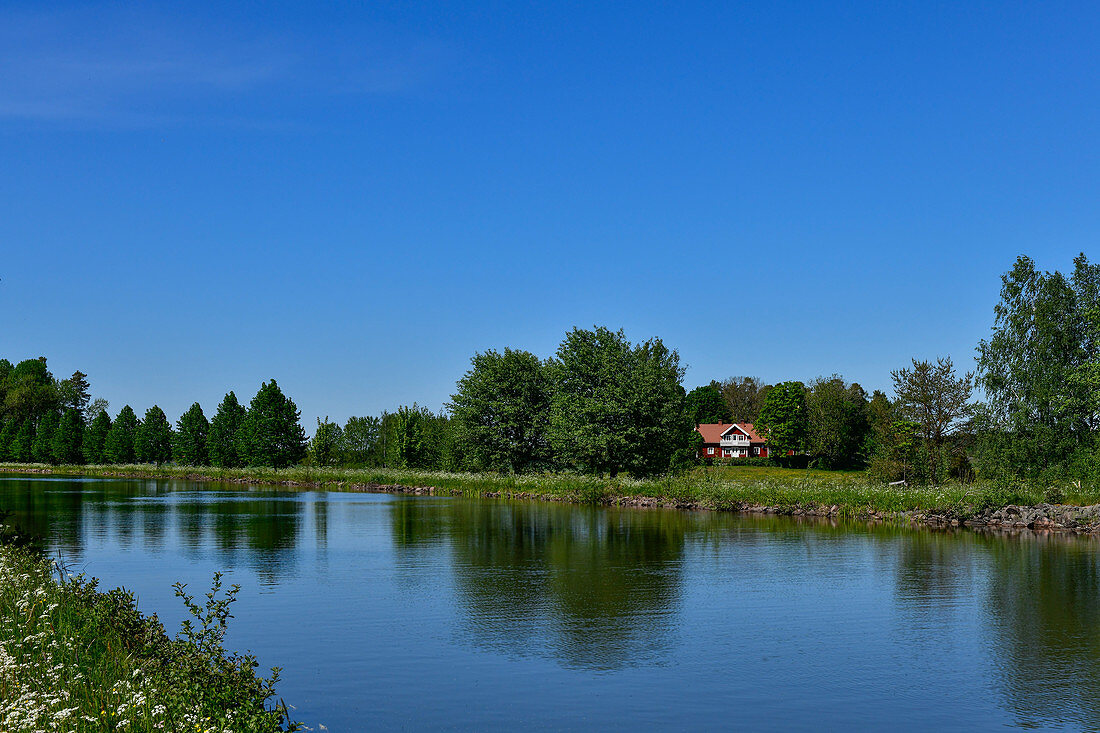 A typical Swedish house is hidden by the Göta Canal in Hajstorp, Västergötland, Sweden