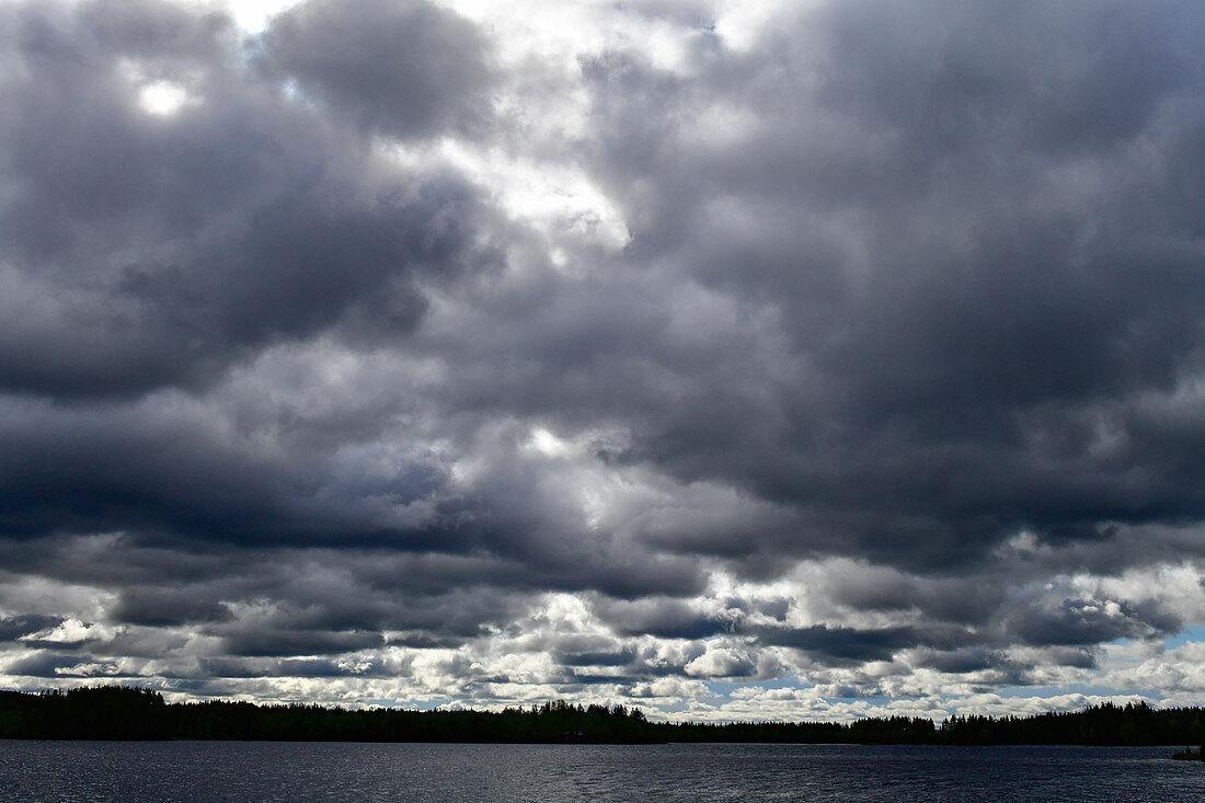 Sehr dunkle Regenwolken über einem See bei Meselefors, Provinz Västernorrland, Schweden