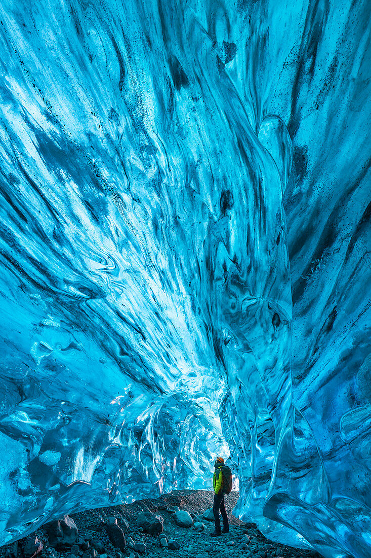Man observes an ice cave of Breidamerkurjokull, Austurland, Iceland, Northern Europe