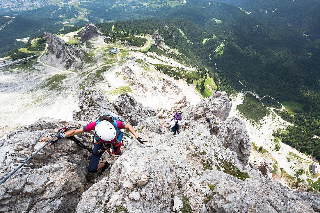 Ein Kletterer entlang des Klettersteigs Olivieri auf dem Tofana di Mezzo mit dem Nationalpark Dolomiti Bellunesi im Hintergrund, Provinz Belluno, Venetien, Italien