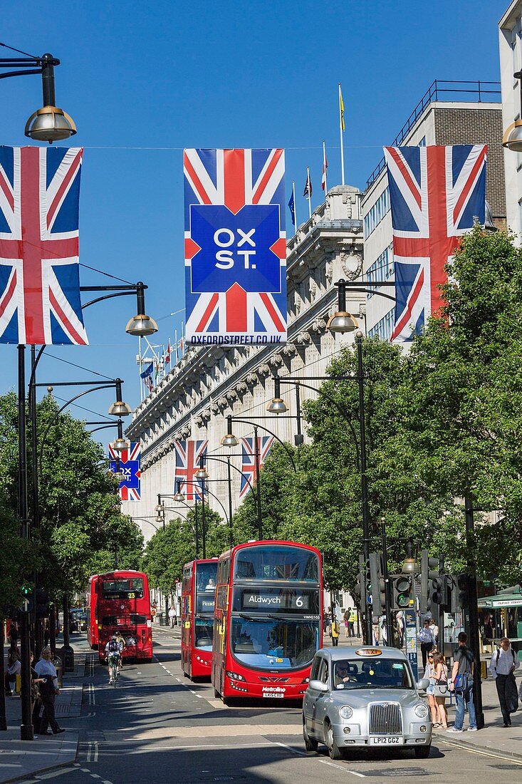 Vereinigtes Königreich, London, Oxford Street zwischen den Stadtteilen Marylebone und Mayfair, das Kaufhaus Selfridges, Doppeldeckerbusse und das graue Londoner Taxi, Flaggen des Vereinigten Königreichs