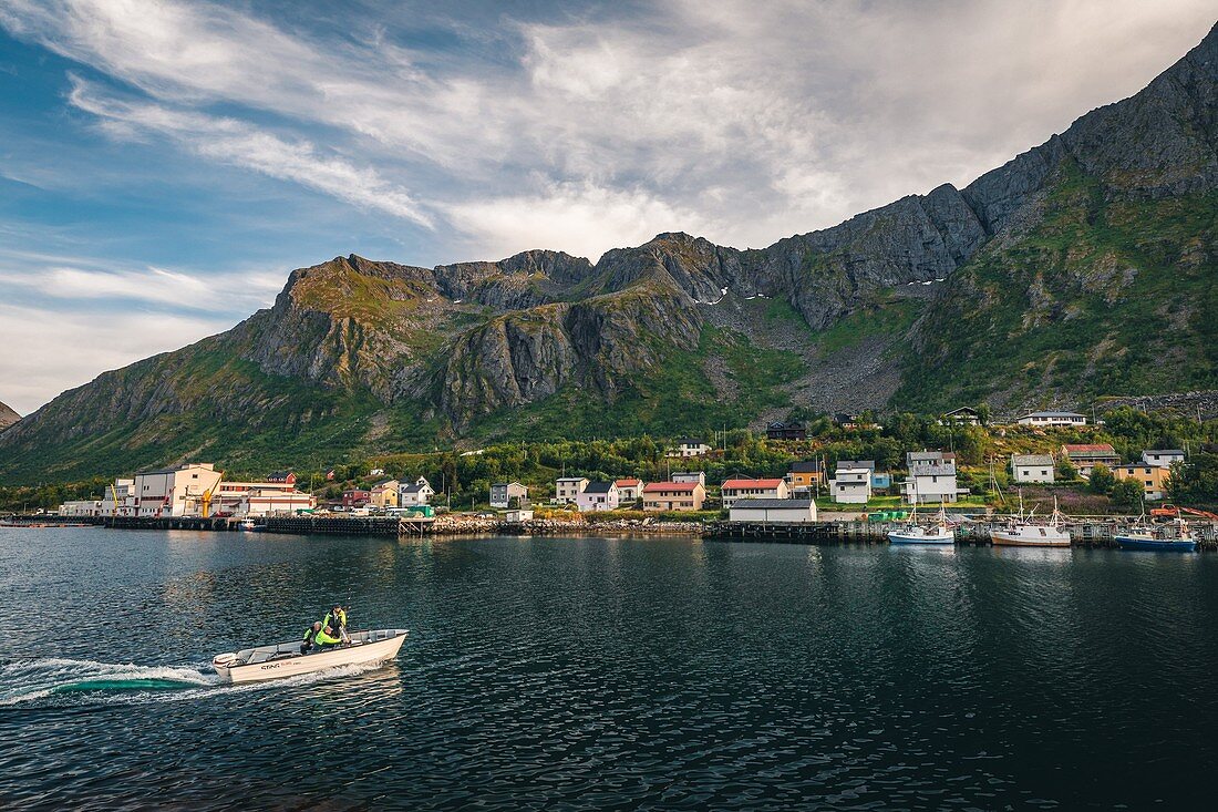 FISHING BOAT ENTERING THE PORT IN THE TOWN OF GRYLLEFJORD SURROUNDED BY MOUNTAINS, SENJA, NORWAY