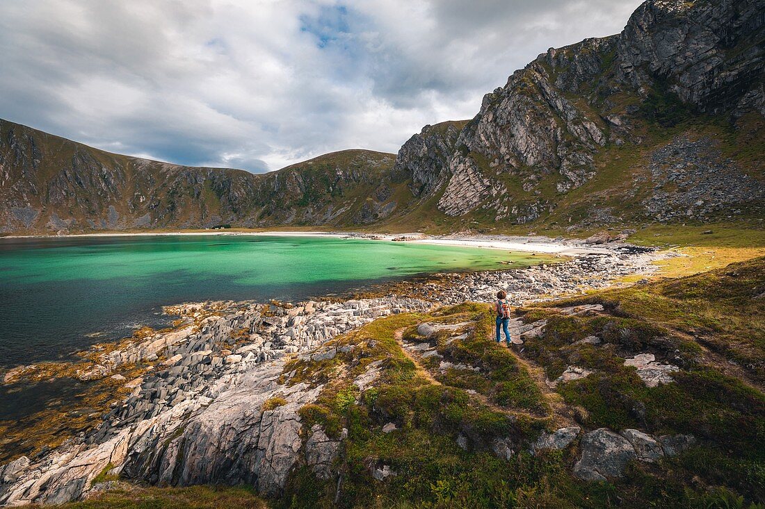 HIKER APPROACHING THE BEACH OF HOYVIKA, WHITE SAND AND TURQUOISE WATER SURROUNDED BY MOUNTAINS, STAVE, ANDOYA, NORWAY