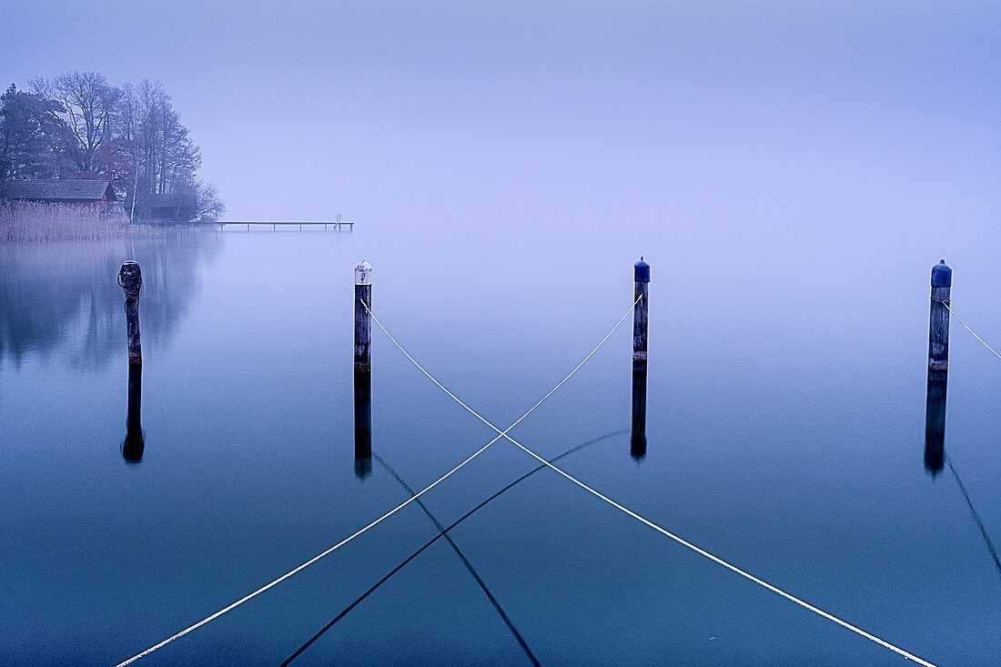 Ropes on wooden posts in the abandoned harbor in winter in Lake Starnberg, Seeseiten, Bavaria, Germany