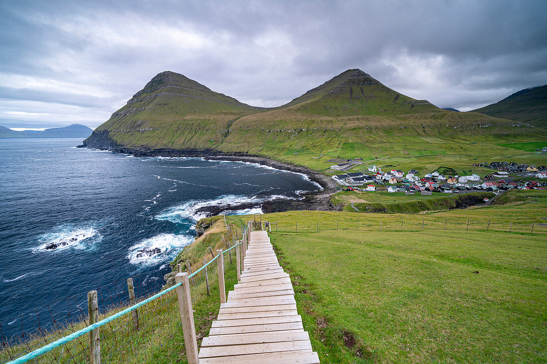 View from the steep coast to the sea. A wooden staircase facilitates the ascent on the steep slope above Gjógv, Faroe Islands.