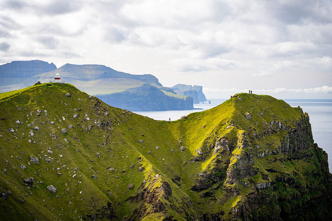 Lighthouse Kallur and tourists at the northern tip of the island Kalsoy, Faroe Islands