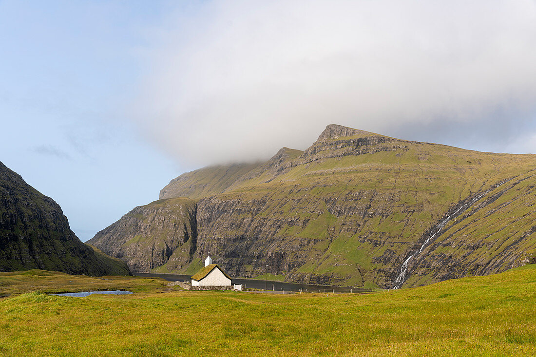 View of the church of Saksun, with a grassy roof in front of the lagoon, Streymoy Island in the Faroe Islands.