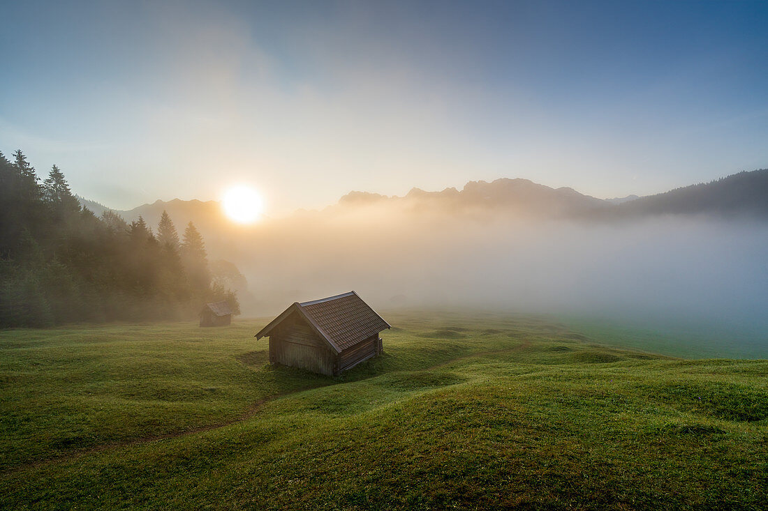 Die kleinen Hütten über dem nebelverhangenen Geroldsee an einem Frühherbstmorgen, Krün, Bayern, Deutschland