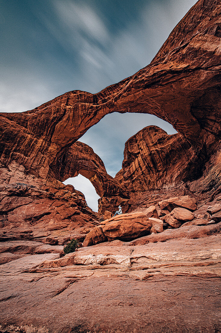 Person sitting under the Double Arch in Arches National Park, Utah, USA, North America