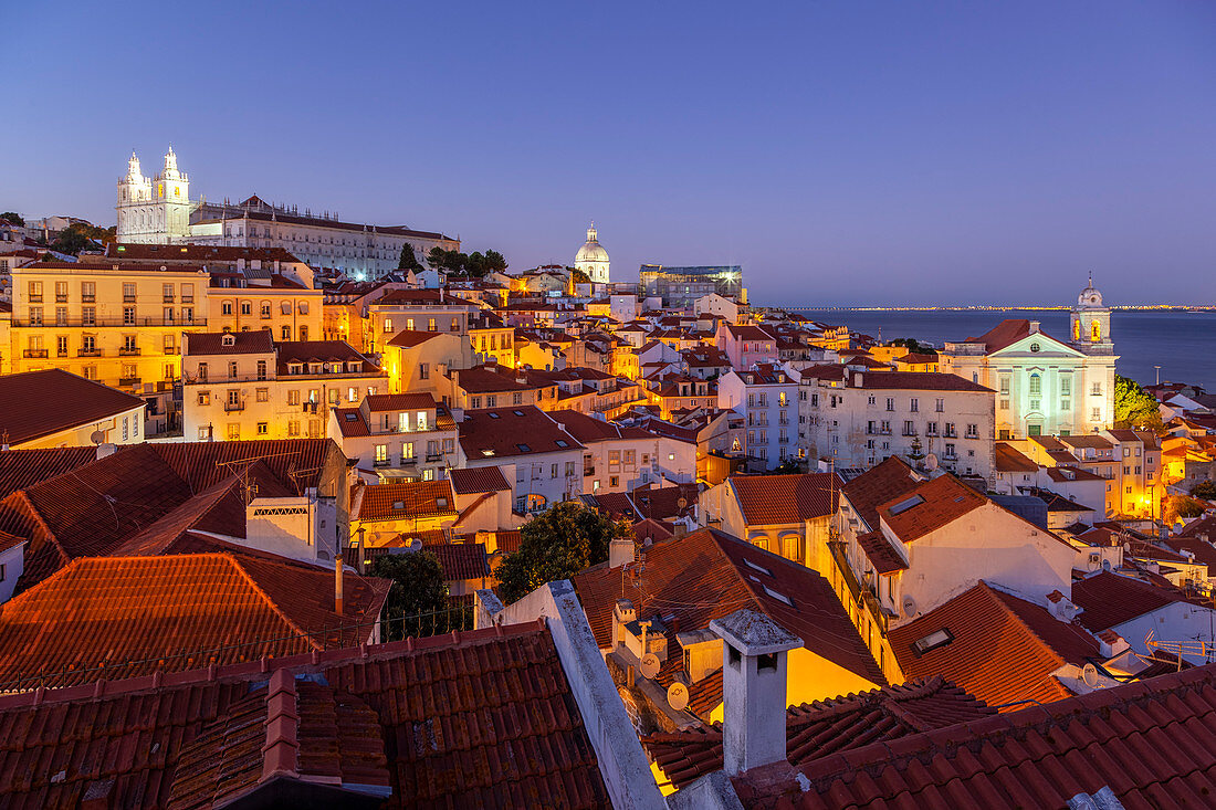 Blick in der Abenddämmerung über die Dächer des Alfama-Viertels mit Igreja de São Vicente de Fora, Igreja de Santa Engràcia und Igreja de São Estevão auf dem Hintergrund von Miraduro de Santa Luzia (Blick auf St. Lucy), Alfama-Viertel, Lissabon, Großraum Lissabon, Portugal