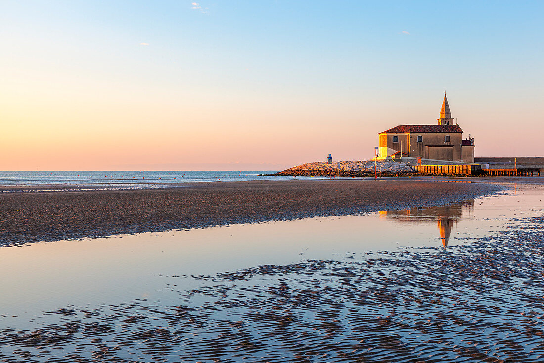 The little church of Madonna dell'Angelo (Church of Blessed Virgin of the Angel) reflected on the shore with low tide, Caorle, Metropolitan CIty of Venice, Veneto, Italy