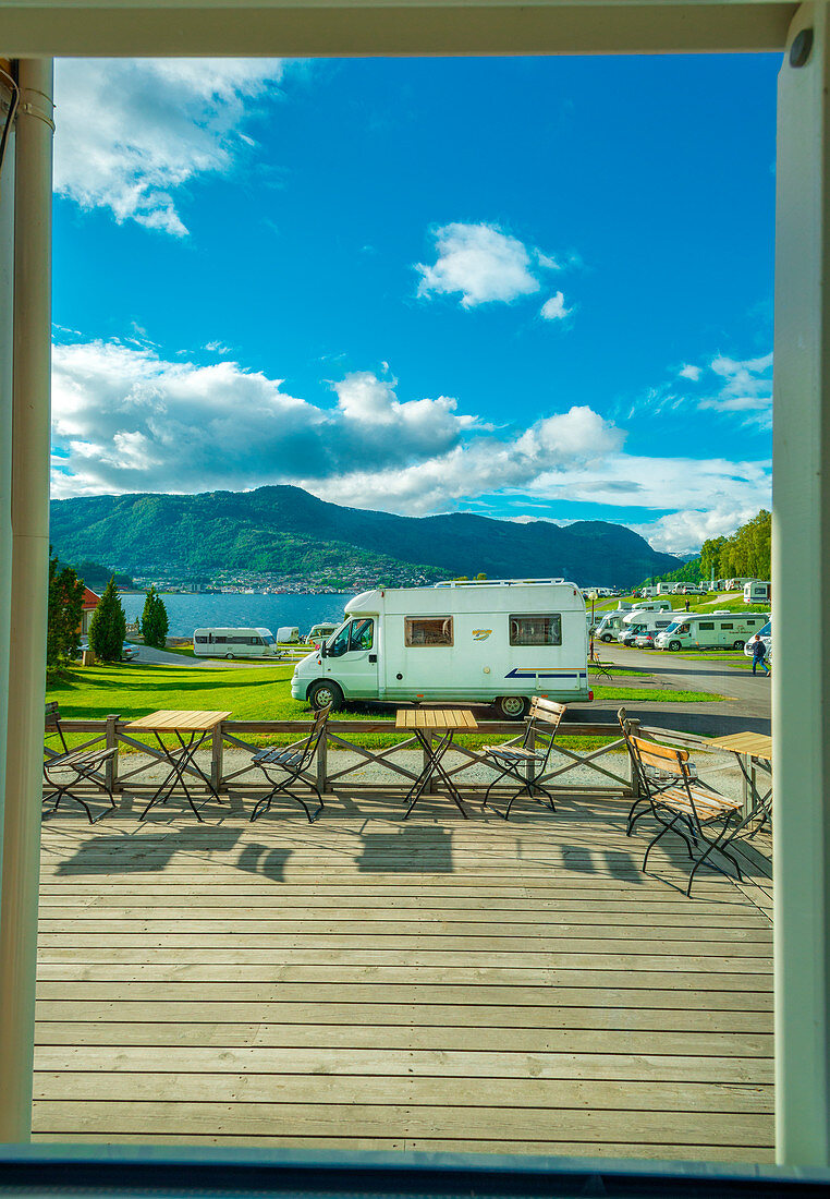 Window view of the campground: campervans, rvs and tents, people enjoying their holidays in Norway