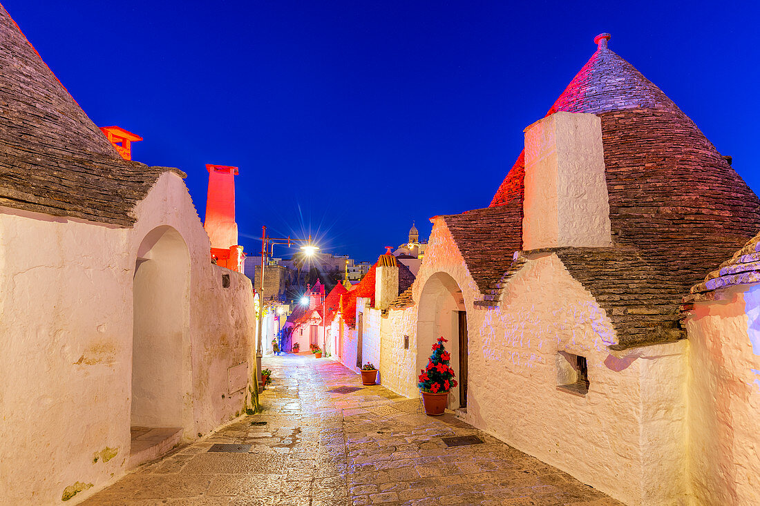 Gasse zwischen Trulli-Häusern, beleuchtet von Weihnachtslichtern, UNESCO-Weltkulturerbe, Alberobello, Provinz Bari, Apulien, Italien, Europa