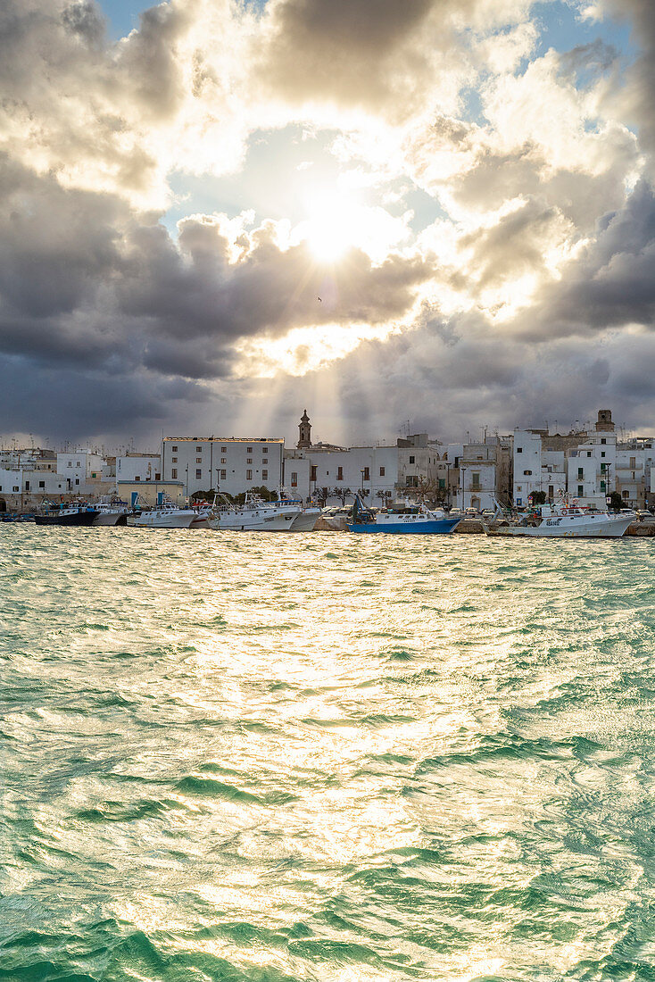 Altstadt beleuchtet von Sonnenstrahlen, die zwischen Wolken ausbrechen, Monopoli, Apulien, Italien, Europa
