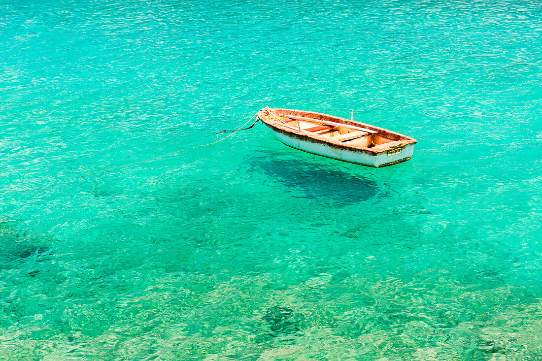 Holzboot schwimmt auf dem kristallklaren und türkisfarbenen Meer in Limeni, Region Mani, Peloponnes, Griechenland, Europa