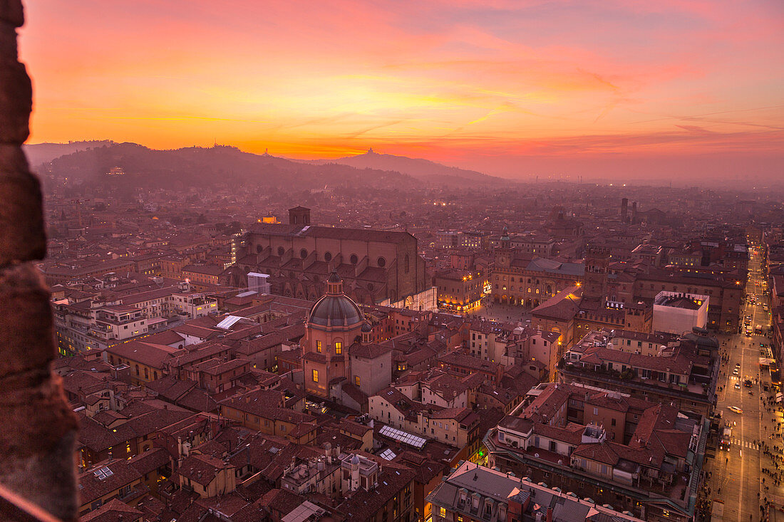 Erhöhtes Stadtbild der Altstadt von Bologna vom Asinelli-Turm bei Sonnenuntergang mit der Kirche San Luca im Hintergrund, Bologna, Emilia Romagna, Italien, Europa