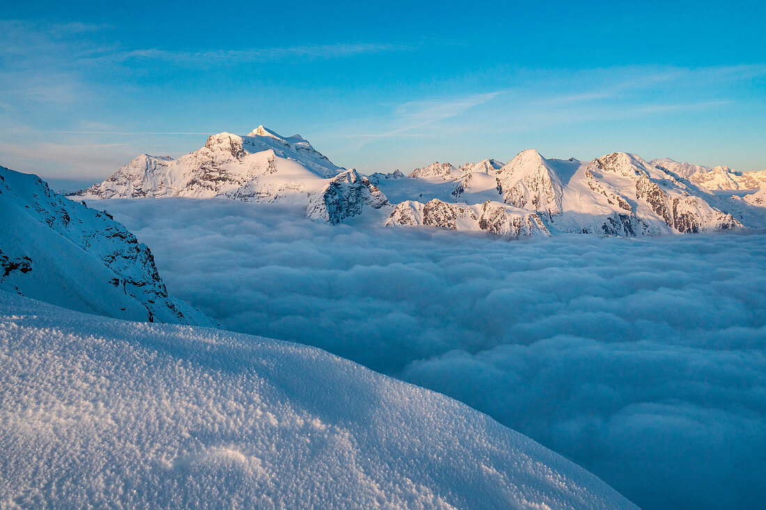 Die Gebirgslandschaft von Grand Combin über einem Wolkenteppich über dem Gipfel des La Sale im Winter, Refuge Igloo des Pantalons Blancs, Heremence, Sion, Kanton Wallis, Schweiz, Europa