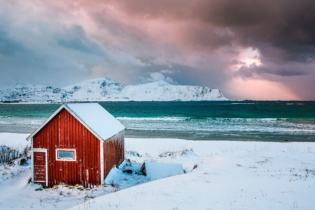 Ein typisches Fischerhaus am verschneiten Rambergstranda, Lofoten, Norwegen
