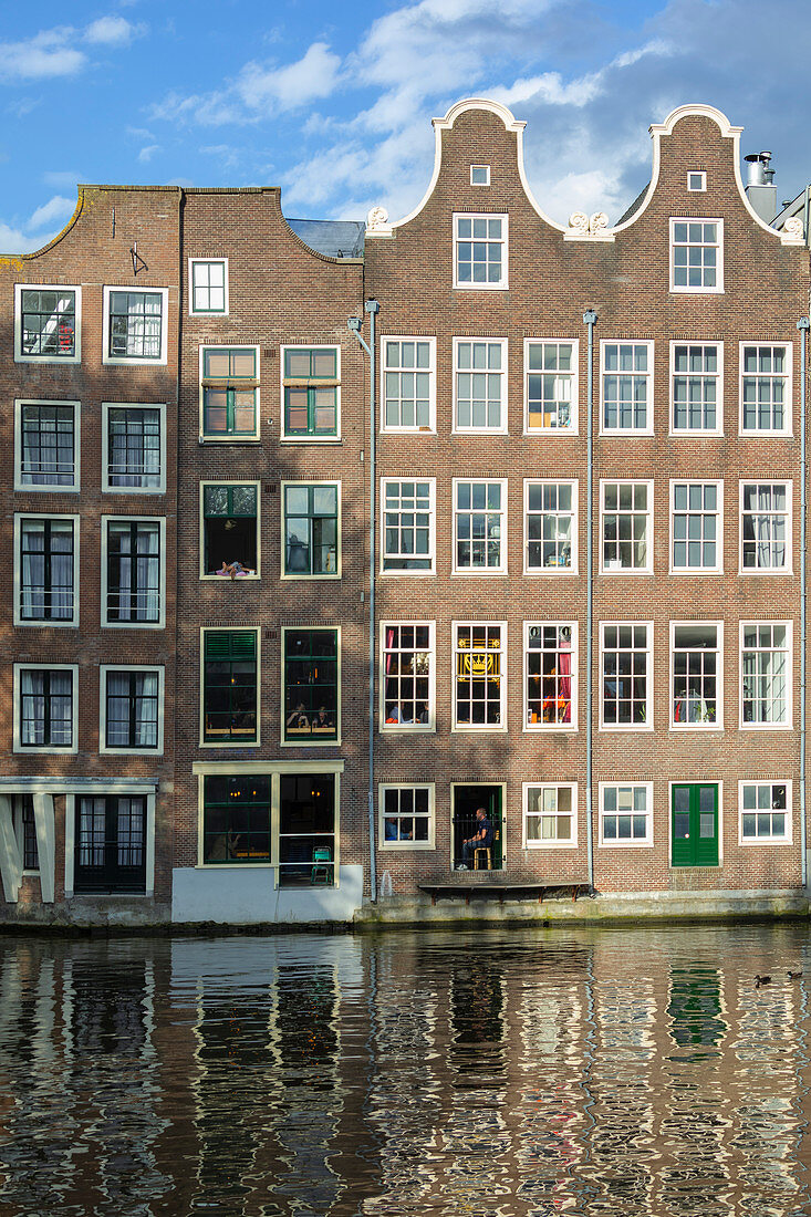 Typical houses reflected on canals in De Wallen district in Amsterdam (North Holland, Netherlands)