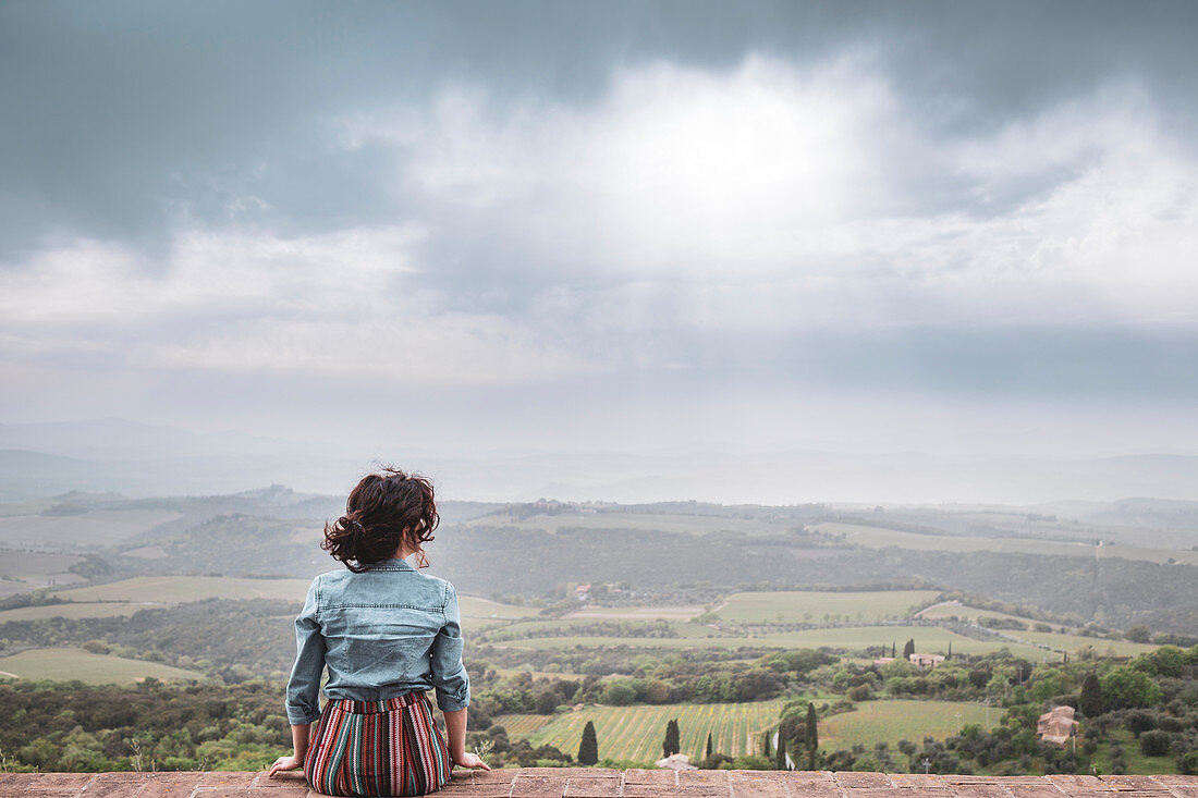 A girl admiring the countryside from Sant'Angelo in Colle, Siena, Tuscany, Italy, Europe
