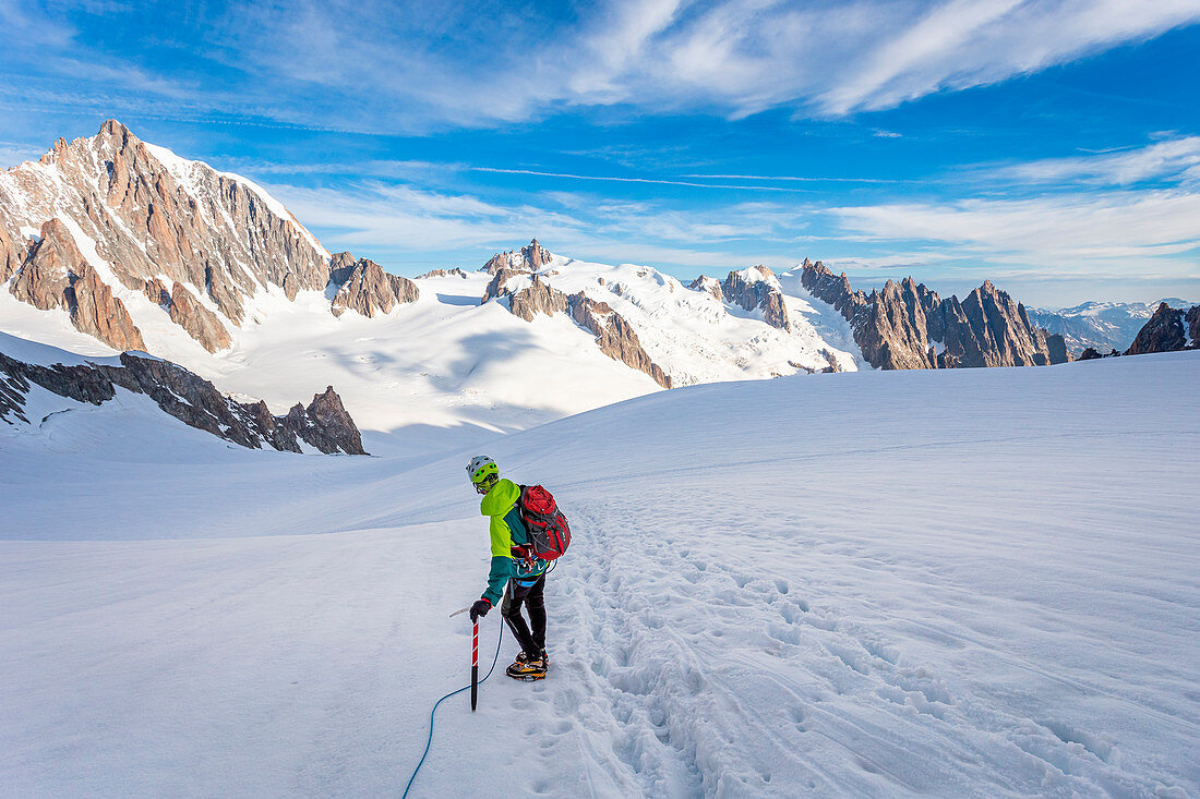 Alpinist über dem Mont-Blanc-Gletscher beim Beobachten der Aiguille du Midi, in der Nähe von Punta Helbronner (3462m), Mont Blanc, Courmayeur, Aosta, Aostatal, Italien