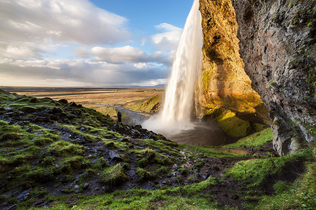 A man observes Seljalandsfoss waterfall, Skógar, Iceland, Northern Europe 