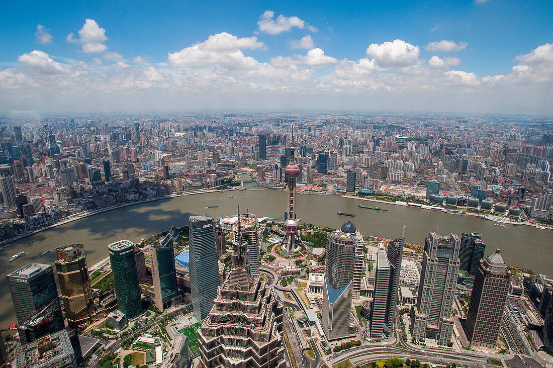 View from the observation level of the 492 meter high World Financial Center in Pudong of downtown, the Oriental Pearl Television Tower, Huangpu River and the Bund in Shanghai, China.