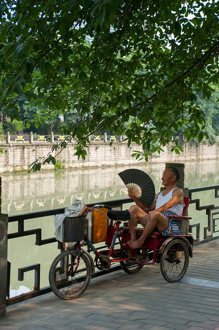 Ein chinesischer Rikschafahrer ruht sich in einem Park in Chengdu, Provinz Sichuan in China aus.