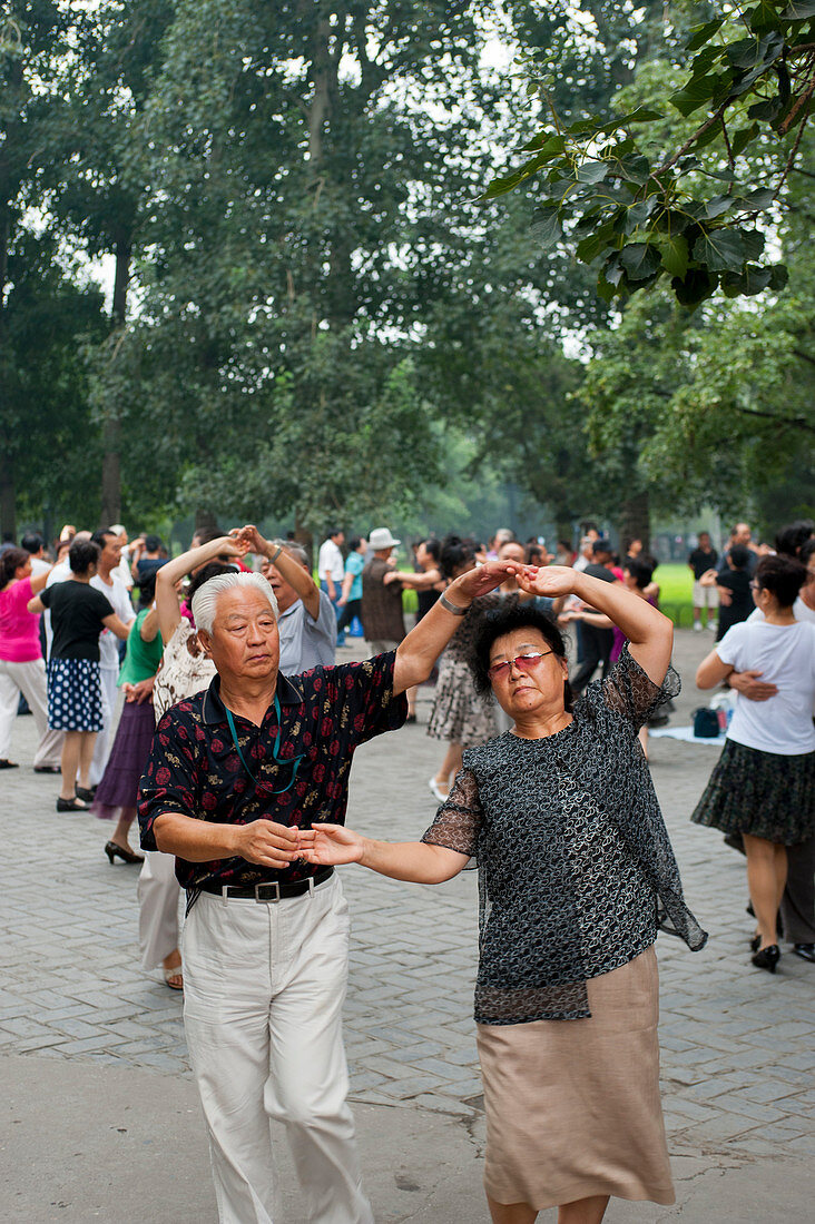 Chinesen gehen tanzend durch einen Park nahe dem Himmelstempel in Peking, China