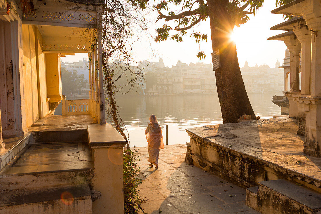 Woman making her way through temple to Pichola Lake in the early morning, Udaipur, Rajasthan, India