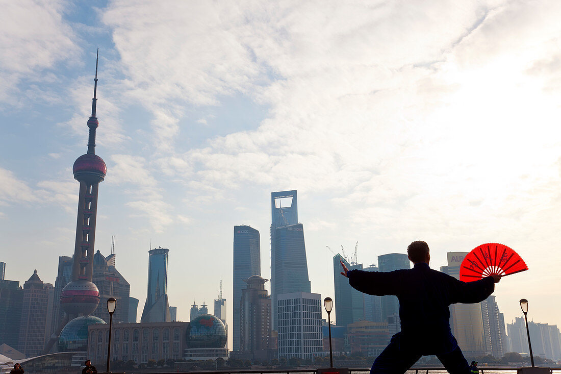 Üben von Tai Chi mit Fächer und Pudong-Skyline, früher Morgen, Shanghai, China