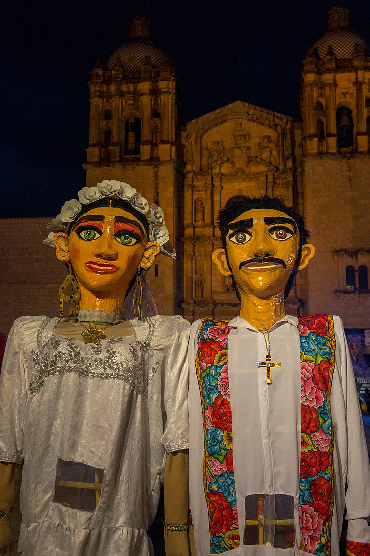 Riesige Puppen verkleidet als Braut und Bräutigam während einer Calenda, einer Prozession durch die Straßen der Innenstadt von Oaxaca, die eine Hochzeit in der Stadt Oaxaca de Juarez, Oaxaca, Mexiko feiert.