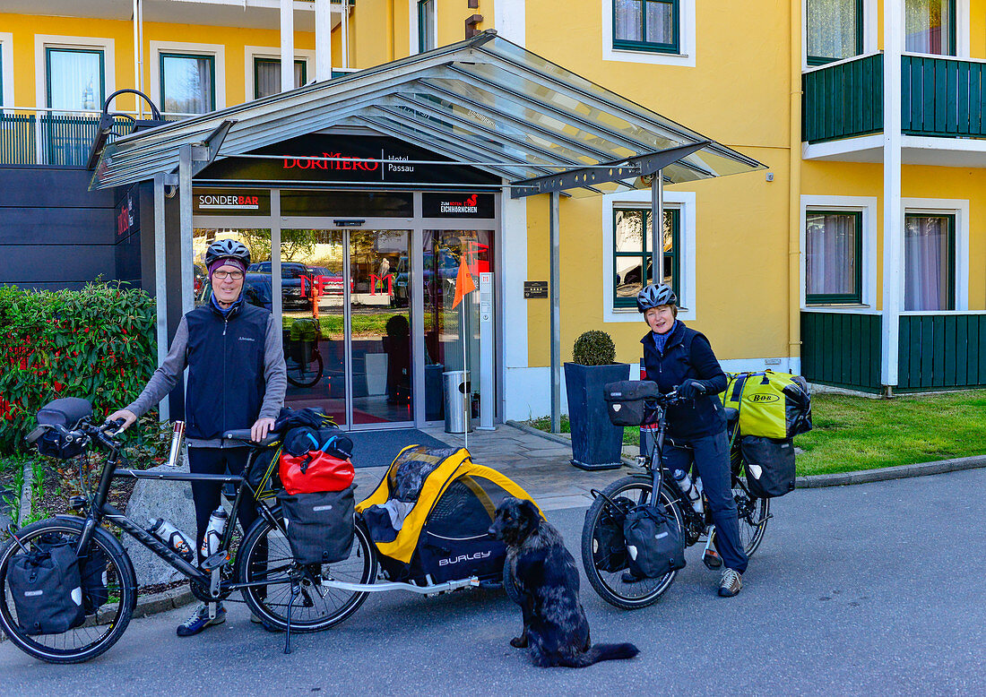 Paar mit bepackten Fahrrädern und Hund auf großer Radtour, Passau, Bayern, Deutschland