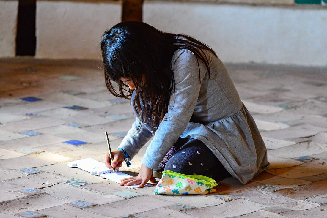 A little girl dreamily paints in a block, Alhambra, Granada, Andalusia, Spain