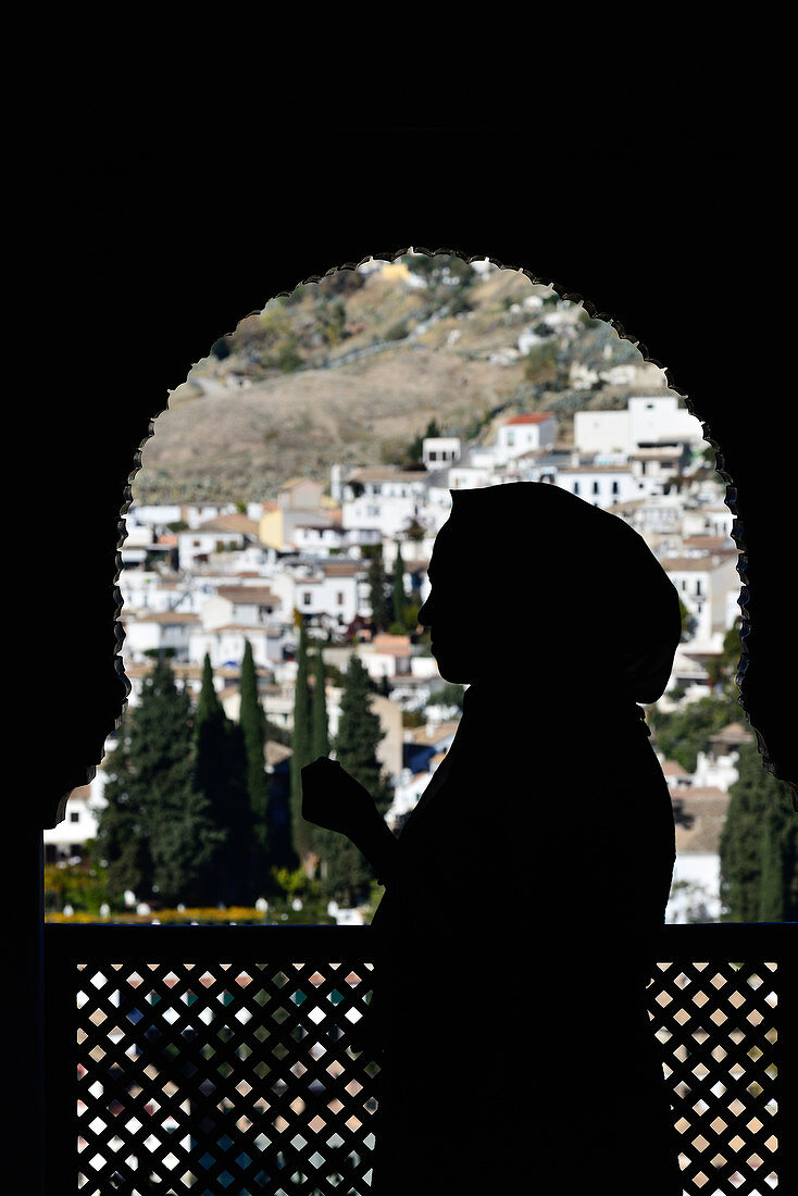 Die Silhouette einer Frau in einem Fenster der Alhambra, Granada, Andalusien, Spanien