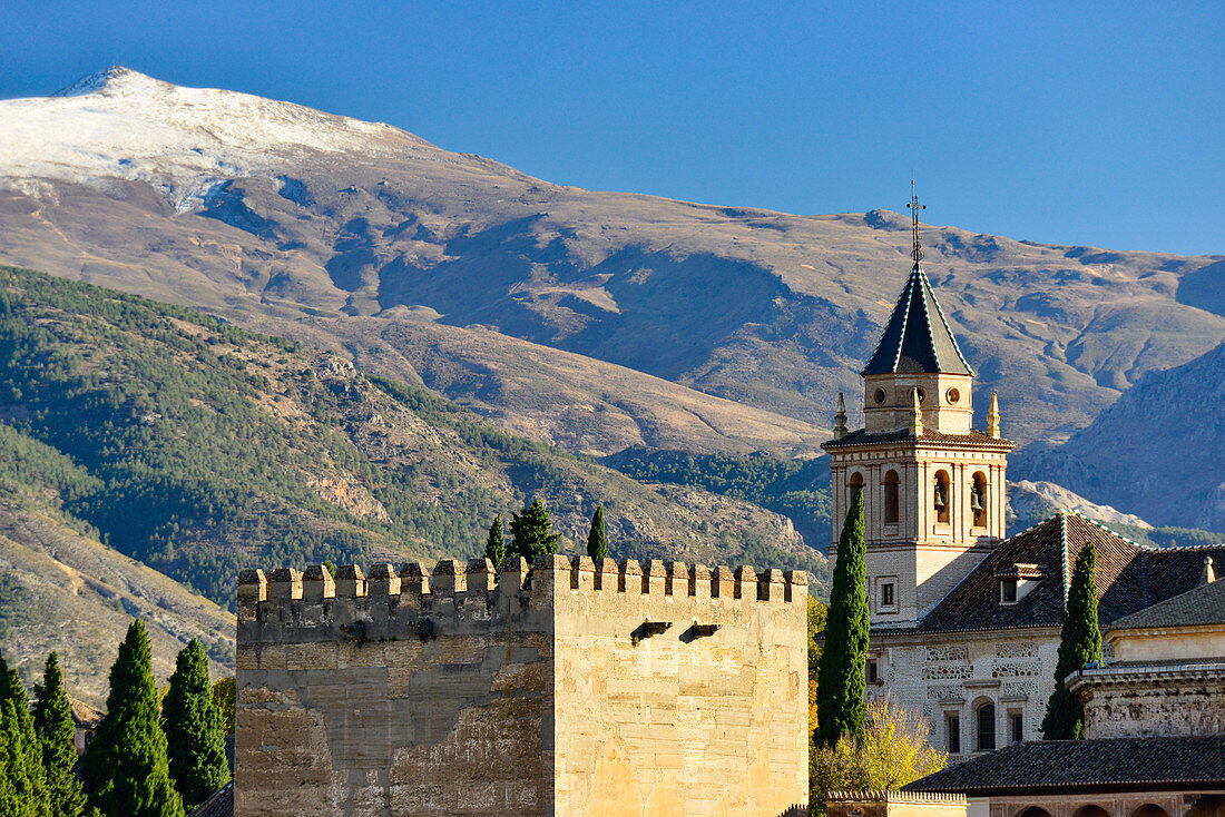 Blick auf einen alten Wehrturm und Kirche vor der Sierra Nevada, Alhambra, Granada, Andalusien, Spanien
