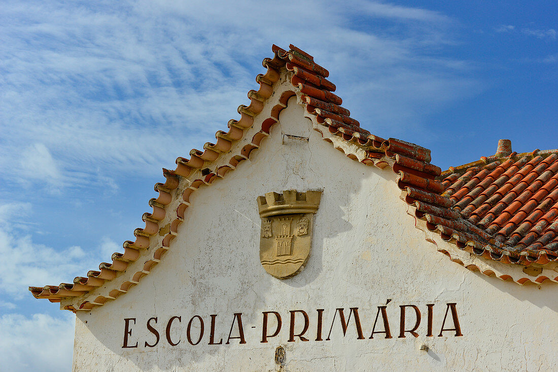 Fassade einer alten Schule mit Wappen und geschwungenem Dach, bei Sagres, Algarve, Portugal